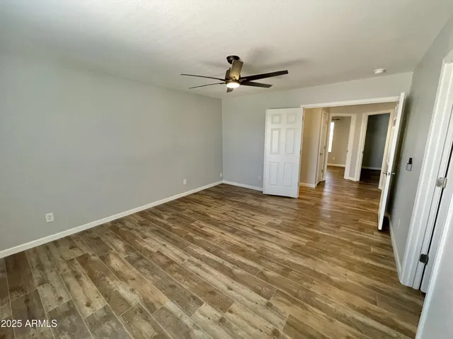 an empty room with wooden floor and fan