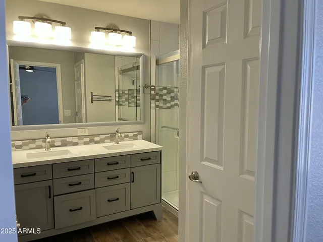 a bathroom with a double vanity sink and mirror with shower