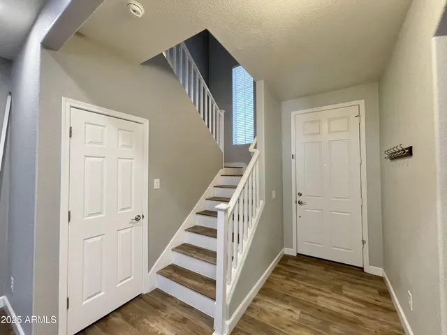 a view of a hallway with stairs and wooden floor