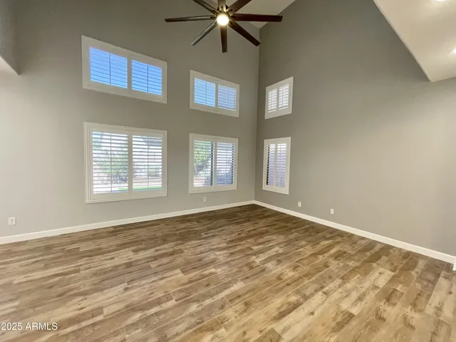 a view of an empty room with window and chandelier fan