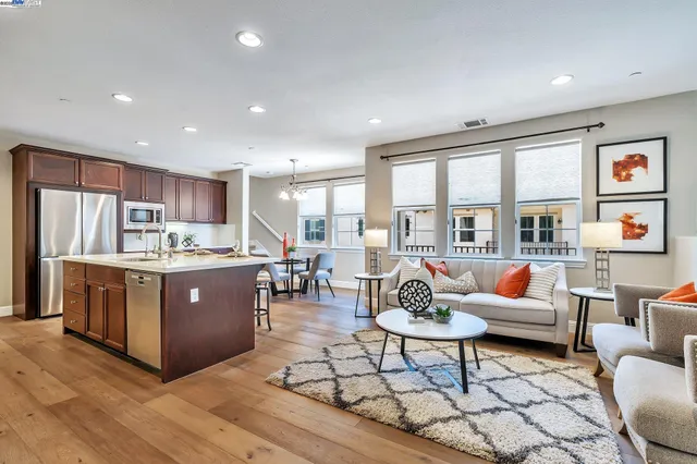 a living room with stainless steel appliances granite countertop furniture a couch a lamp and a view of kitchen