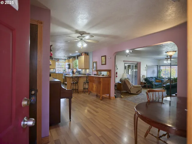 a living room with couches and kitchen view with wooden floor