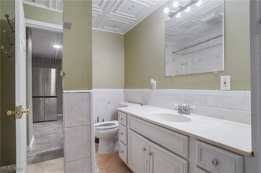 888 Dan Street Akron, OH 44310 - Photo 20 of 36 Bathroom featuring coffered ceiling, tile patterned flooring, toilet, vanity, and tile walls