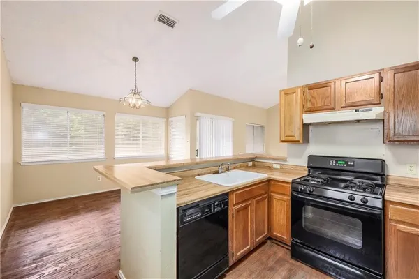 a kitchen with a stove a sink and a wooden floor