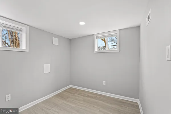 a view of an empty room with wooden floor and window
