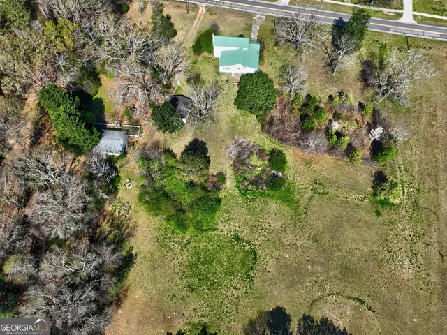 an aerial view of residential house with outdoor space and trees all around