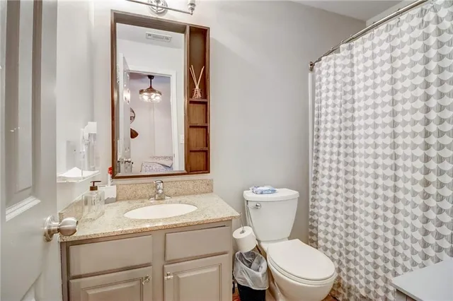 a bathroom with a granite countertop toilet a sink and a mirror