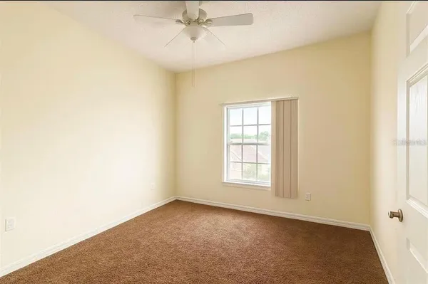 an empty room with windows and fan
