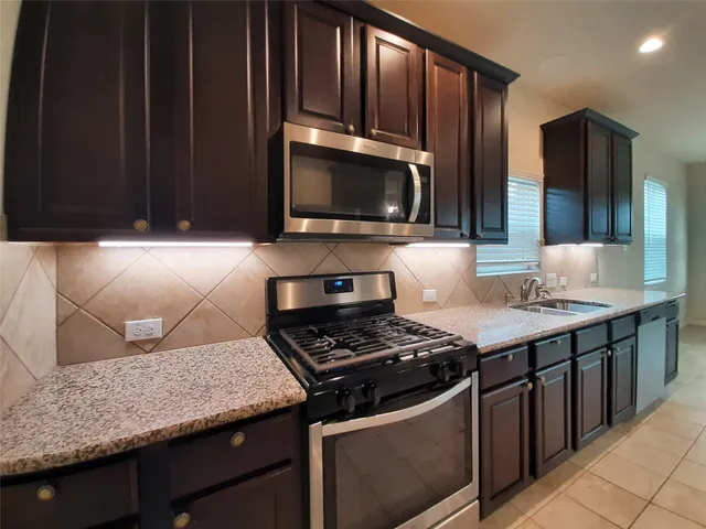 a kitchen with granite countertop a stove top oven microwave and cabinets