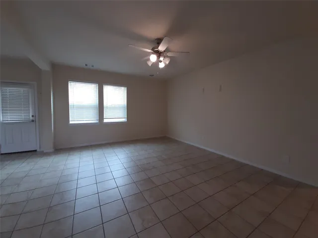 an empty room with windows and ceiling fan