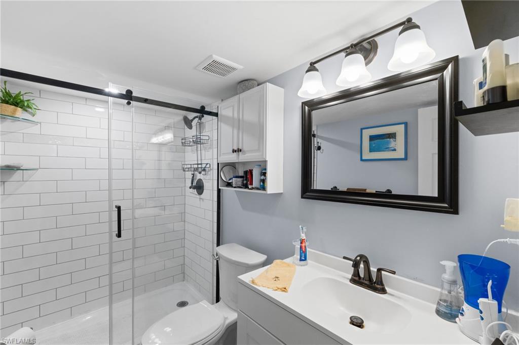 1686 Blue Point Avenue, Unit A1 Naples, FL 34102 - Photo 18 of 38 a bathroom with a sink mirror and shower