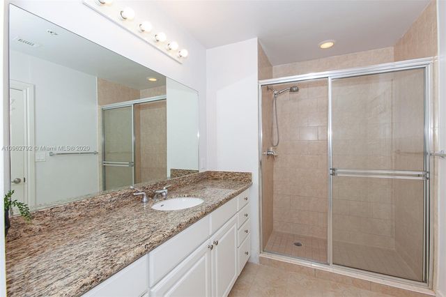 a bathroom with a granite countertop sink mirror and shower