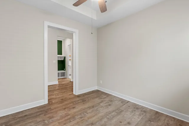 an empty room with wooden floor a ceiling fan and windows