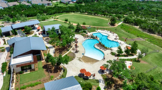 a view of a swimming pool with lawn chairs and large trees