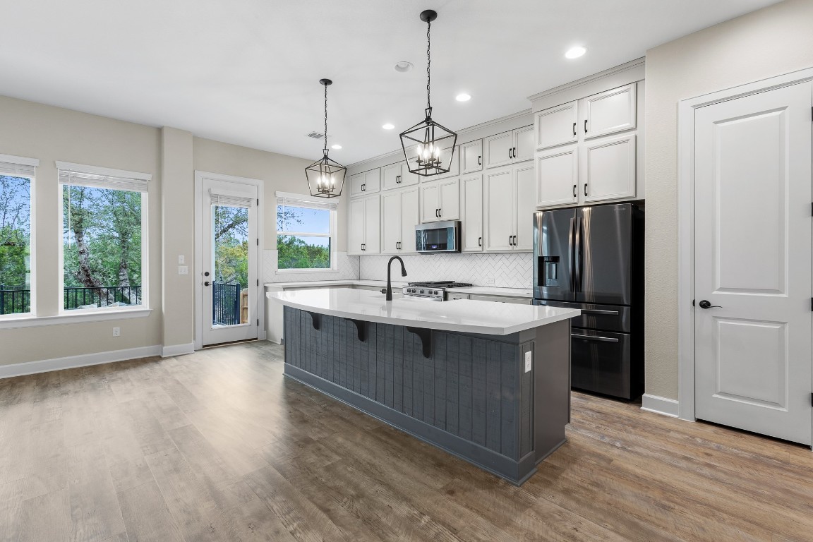 1046 Hazy Hills Loop Dripping Springs, TX 78620 - Photo 6 of 35 a kitchen with stainless steel appliances granite countertop a sink a stove a refrigerator and island with wooden floor