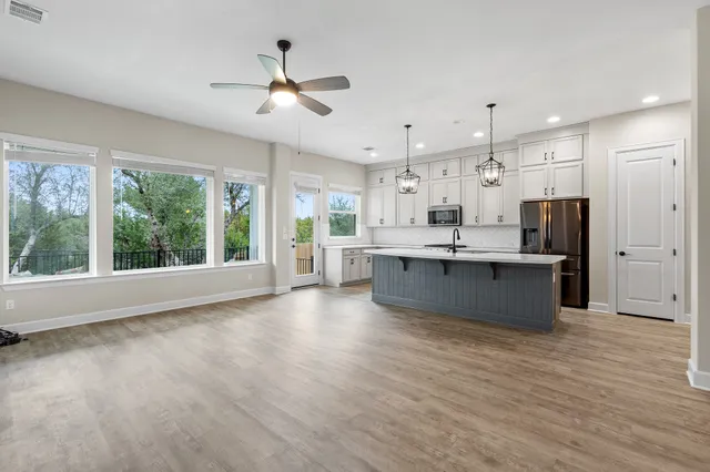 a large kitchen with stainless steel appliances kitchen island a large counter top and a wooden floors