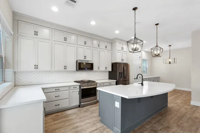 a large kitchen with stainless steel appliances kitchen island granite countertop a large counter top and a view of living room