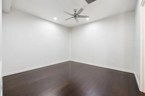 an empty room with wooden floor and ceiling fan