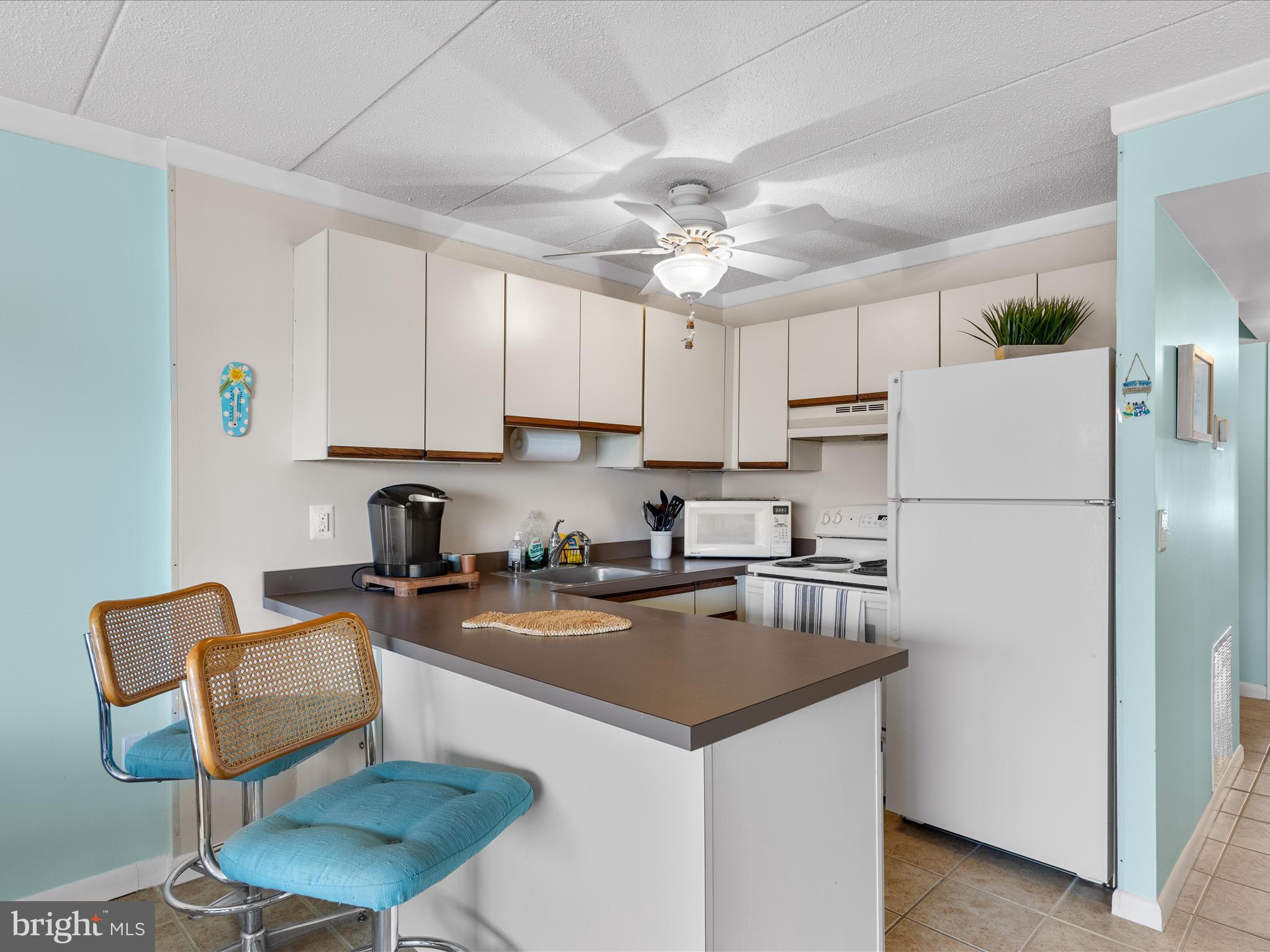 17 70th Street, Unit 25 Ocean City, MD 21842 - Photo 12 of 37 a kitchen with stainless steel appliances granite countertop a refrigerator a sink a stove a dining table and chairs with wooden floor