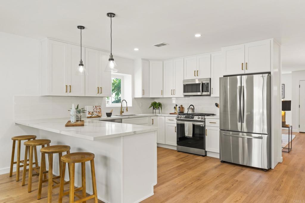 a kitchen with stainless steel appliances granite countertop a refrigerator a stove a sink and a refrigerator