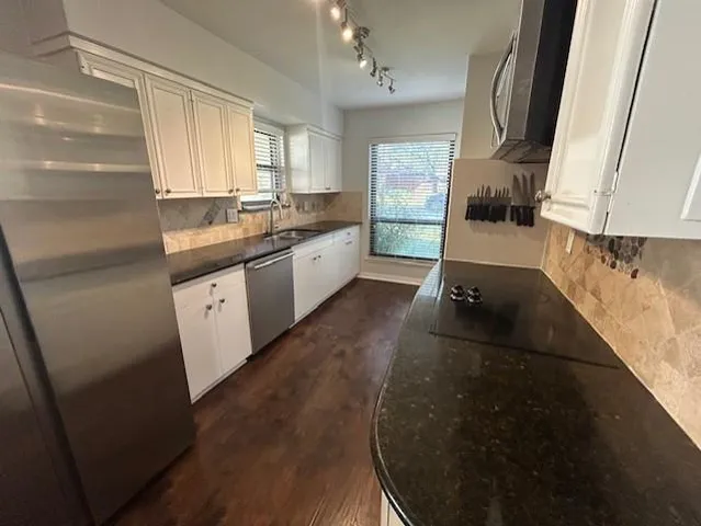 a kitchen with granite countertop white cabinets a sink and a stove
