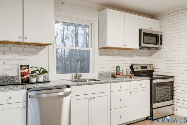 a kitchen with granite countertop white cabinets and white appliances