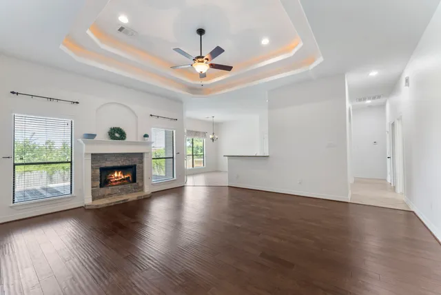 an empty room with wooden floor fireplace fan and windows