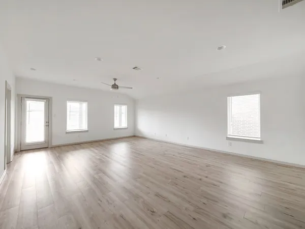 a view of an empty room with wooden floor and window