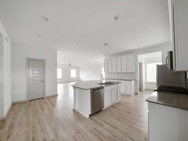 a kitchen with stainless steel appliances granite countertop a stove a sink and white cabinets