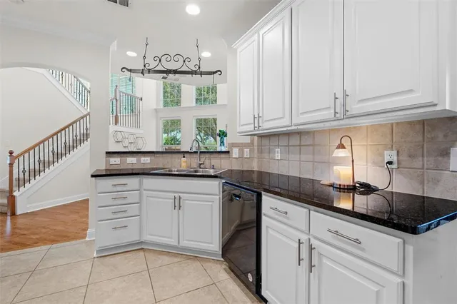 a kitchen with granite countertop white cabinets stainless steel appliances and a sink