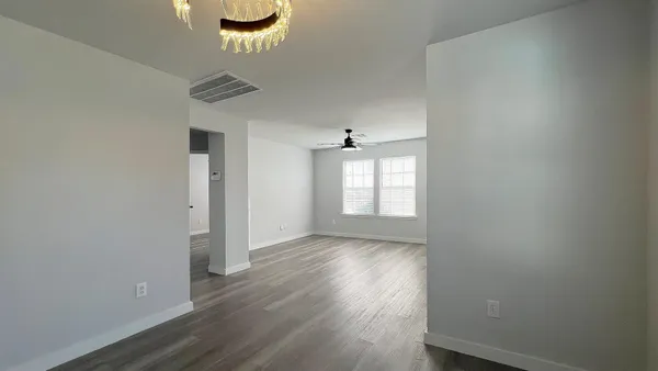 an empty room with wooden floor ceiling fan and windows