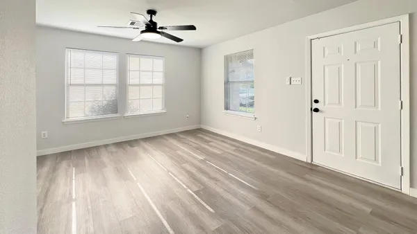 an empty room with a window and a fan