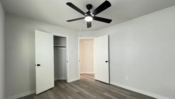 an empty room with ceiling fan and window