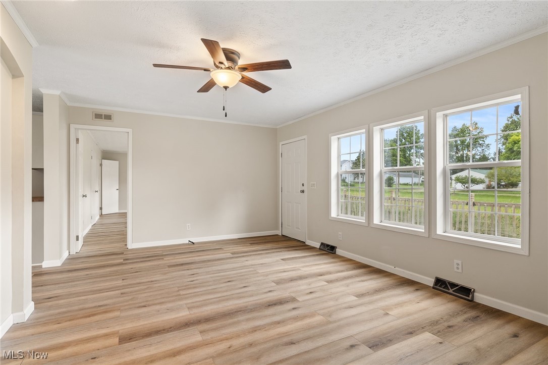 4838 Angling Rd Extension Wooster, OH 44691 - Photo 8 of 39 Empty room with a ceiling fan, light wood finished floors, and crown molding