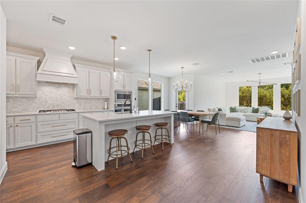 5244 Ranchero Trail Fort Worth, TX 76126 - Photo 6 of 33 Kitchen with a breakfast bar area, tasteful backsplash, white cabinets, pendant lighting, and a center island with sink