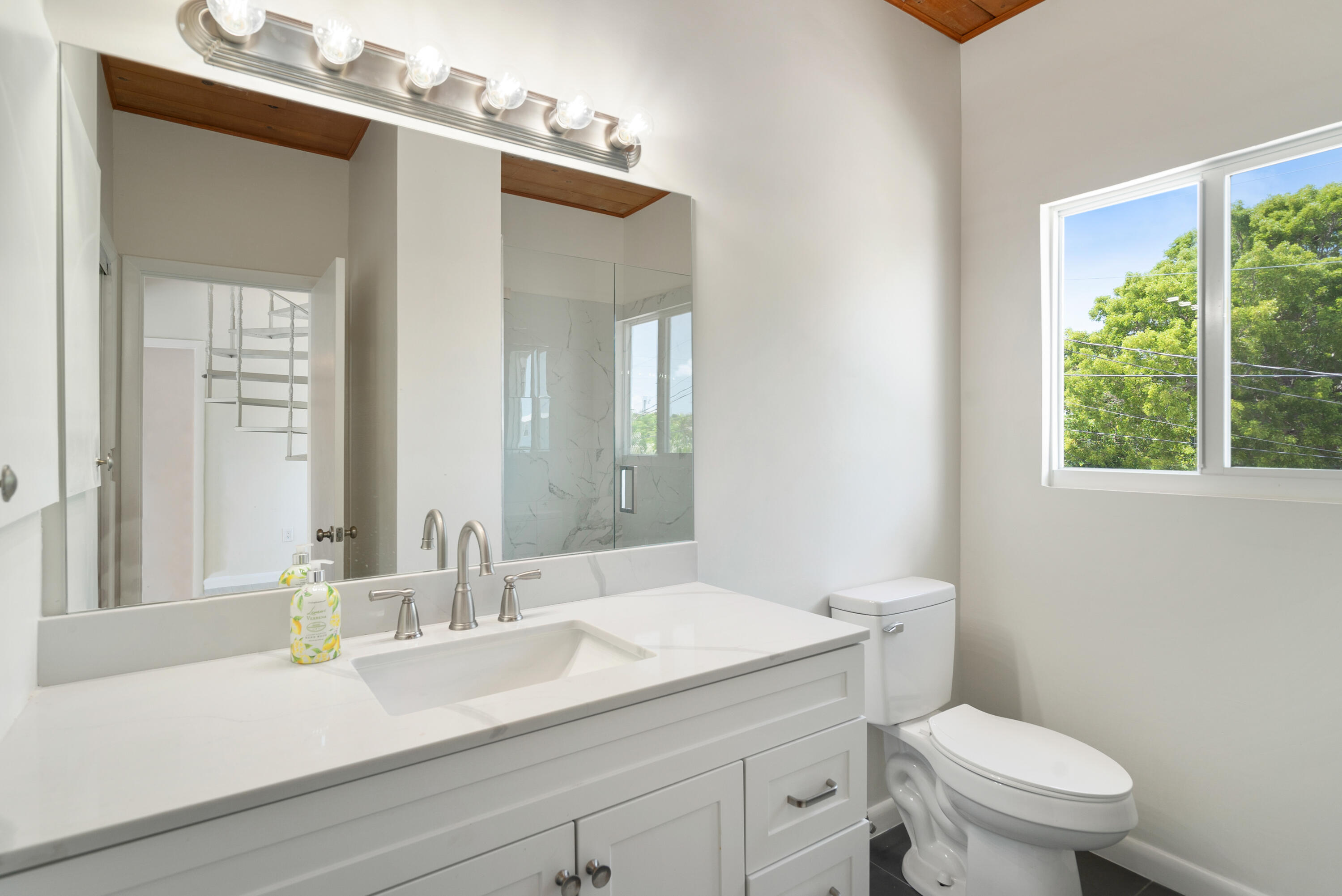415 Big Pine Road Key Largo, FL 33037 - Photo 12 of 35 a bathroom with a granite countertop toilet a sink and a mirror