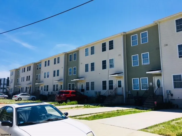 a front view of a building with garden and trees