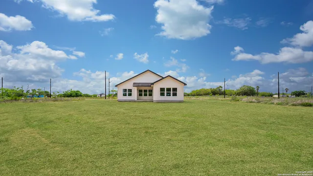 a view of a house next to a big yard and large trees