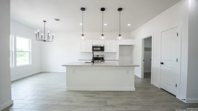 a view of living room with granite countertop kitchen island stainless steel appliances wooden floor and window