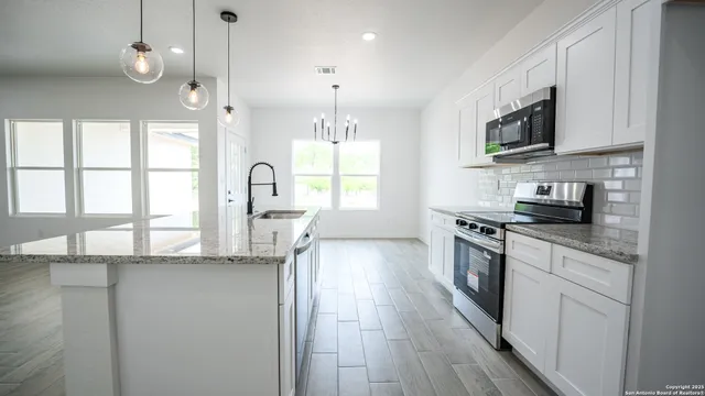 a kitchen with stainless steel appliances granite countertop a sink a stove and a wooden floors