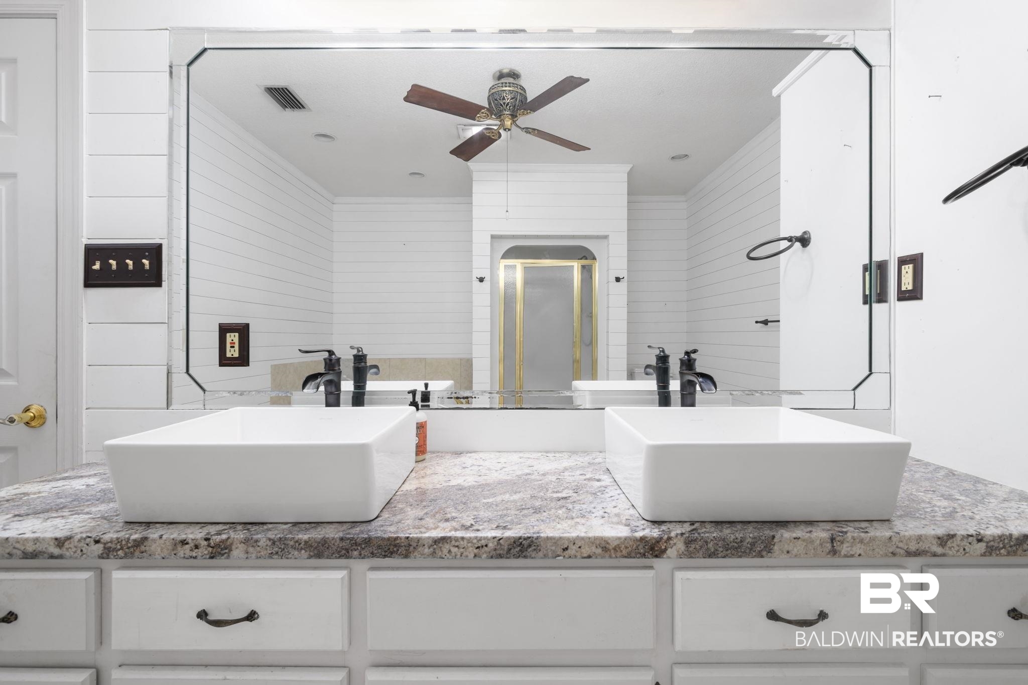 7540 2 Mile Road Irvington, AL 36544 - Photo 38 of 82 Dual vessel sinks with matte black fixtures set on a speckled countertop