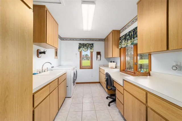 a large white kitchen with a sink a window and stainless steel appliances