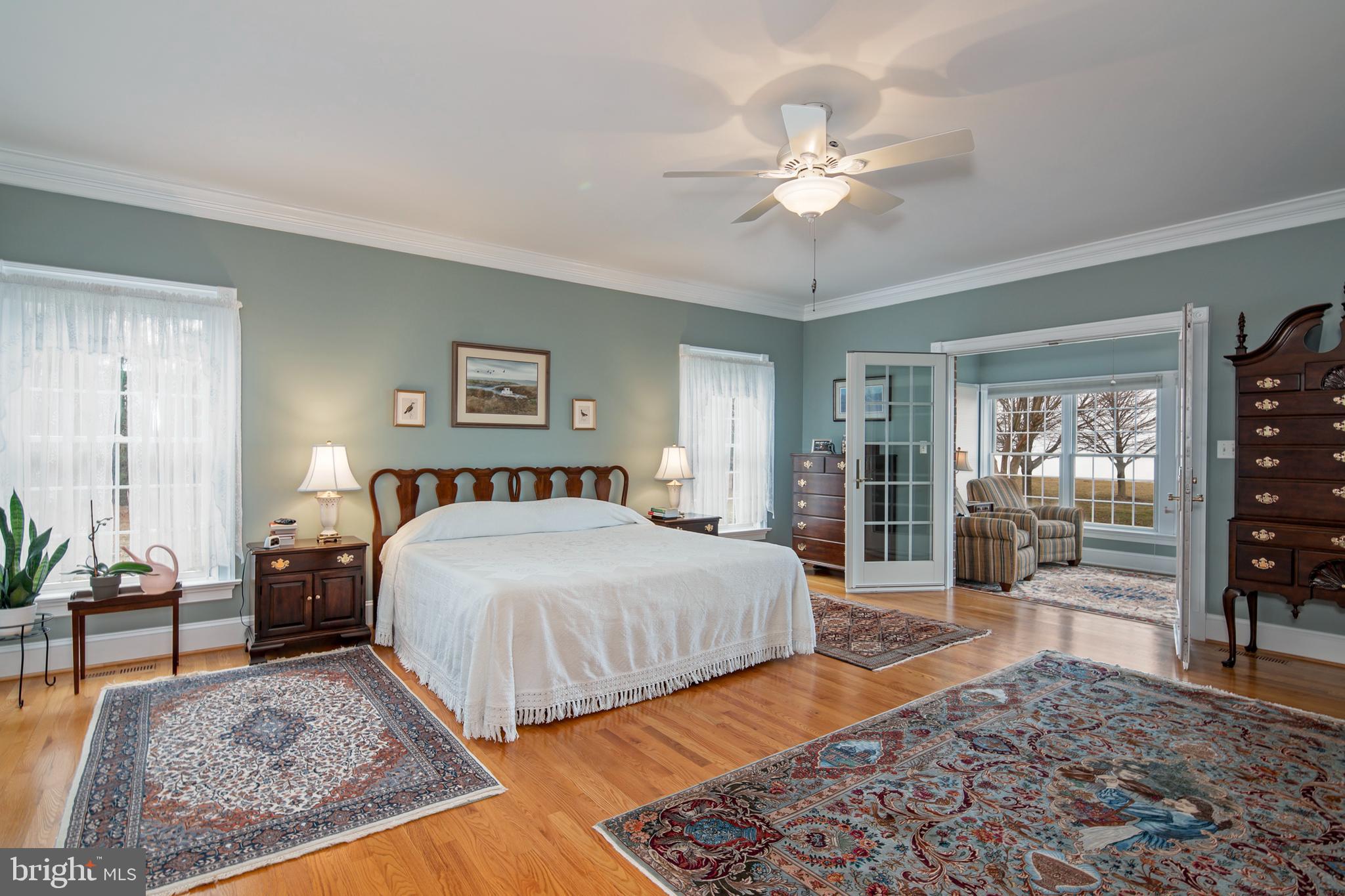 8781 Tilghman Island Road Wittman, MD 21676 - Photo 37 of 60 a spacious bedroom with a large bed and a chandelier