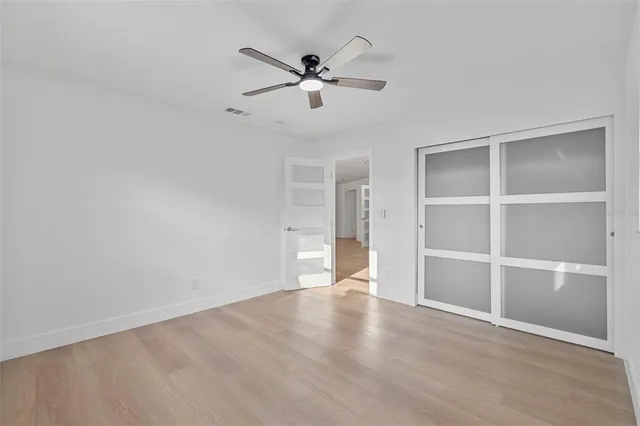 a view of an empty room with a window and wooden floor