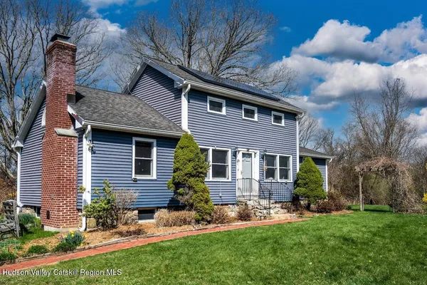 a brick house with a yard plants and a large tree