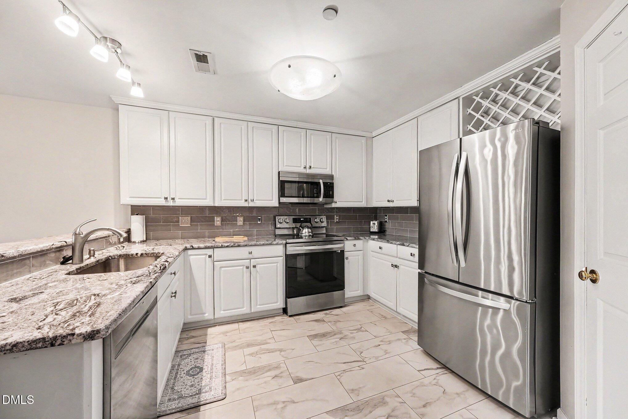 132 Springfork Drive Cary, NC 27513 - Photo 16 of 28 a kitchen with stainless steel appliances granite countertop a refrigerator sink and stove