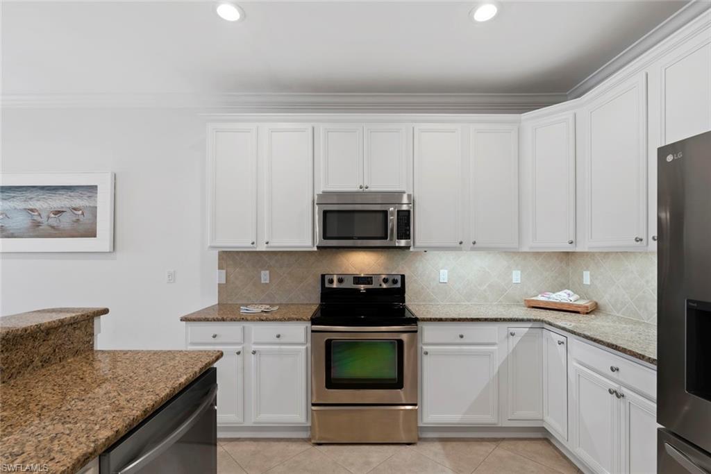 5868 Constitution Street Ave Maria, FL 34142 - Photo 11 of 33 a kitchen with granite countertop white cabinets and black appliances