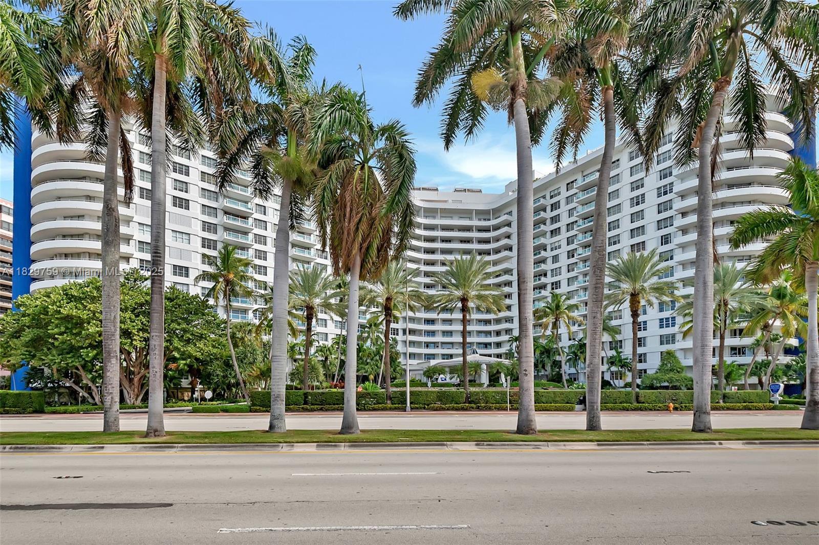 5151 Collins Avenue, Unit 729 Miami Beach, FL 33140 - Photo 2 of 35 a view of a tall building next to a yard with a palm trees