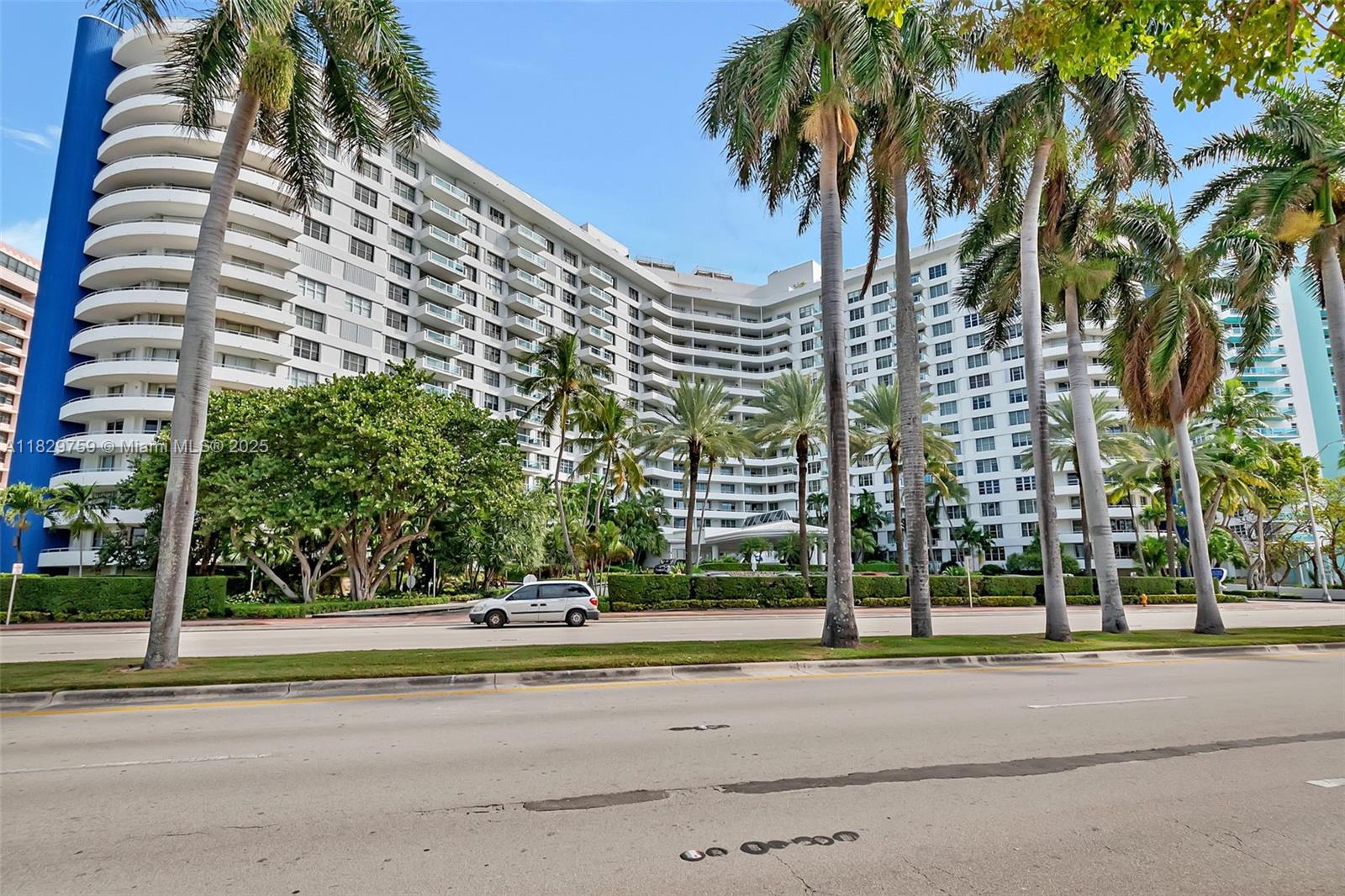 5151 Collins Avenue, Unit 729 Miami Beach, FL 33140 - Photo 34 of 35 a view of a tall building next to a road with a palm trees