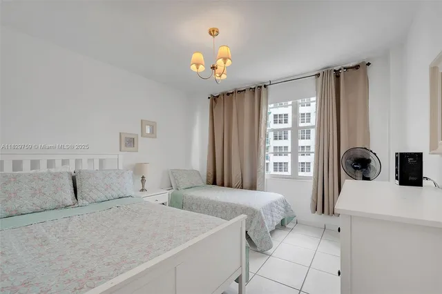 a bedroom with a bed a dresser and a chandelier